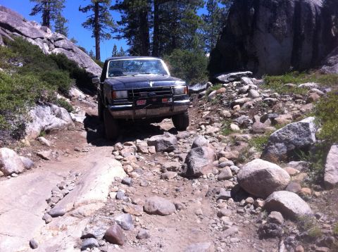 1990 Ford Bronco - This SUV navigates a challenging rocky trail, its body style suggesting a late 1980s model.