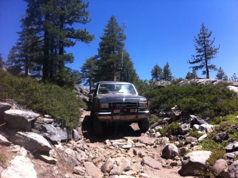1990 Ford Bronco - 1990 Ford Bronco navigating a challenging rocky off-road trail.