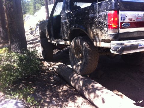 1990 Ford Bronco - Ford Bronco navigating a difficult off-road obstacle on a sunny day.