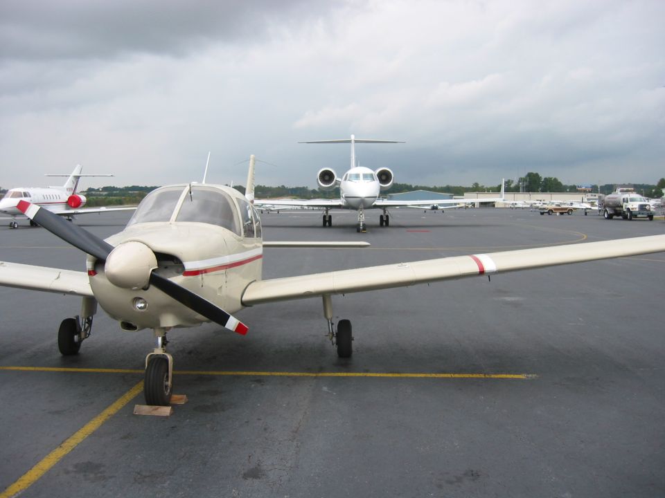 Single-engine tan propeller airplane parked on an airport ramp