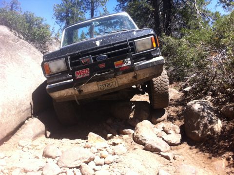 1990 Ford Bronco - Ford Bronco tackling a challenging rock crawling trail with steep inclines and large boulders.