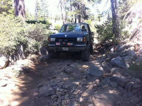 1990 Ford Bronco - Ford Bronco driving on a challenging, rocky off-road trail.