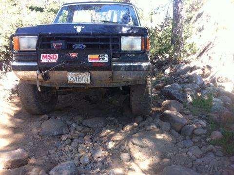 1990 Ford Bronco - This black Ford Bronco is navigating a challenging, rocky trail.