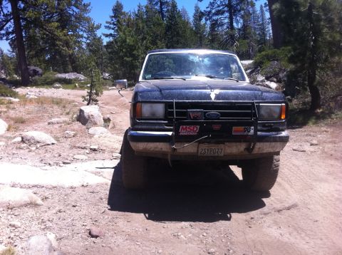 1990 Ford Bronco - This Ford Bronco is parked on a dirt trail in a wooded, rocky area.