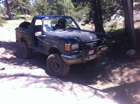 1990 Ford Bronco - 1990 Ford Bronco navigating a rocky off-road trail in the mountains.