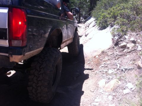1990 Ford Bronco - This 1990 Ford Bronco navigates a challenging off-road path in a wooded, rocky area.