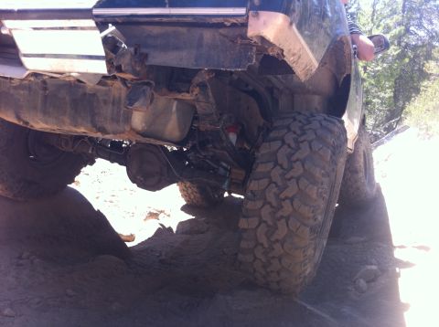 1990 Ford Bronco - The rear axle and suspension of a vehicle are visible as it navigates a rough, rocky terrain.
