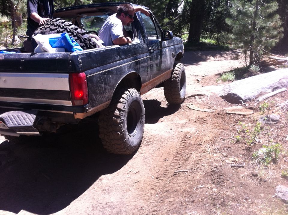Black SUV with large off-road tires on a dirt trail