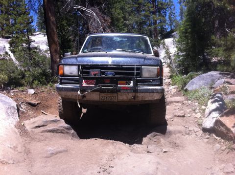 1990 Ford Bronco - Ford Bronco navigating a challenging rocky trail during an off-road excursion.