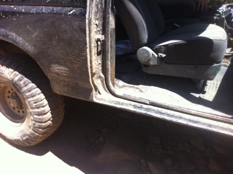 1990 Ford Bronco - Muddy 1990 Ford Bronco interior with a view of the driver's seat and exterior wheel.