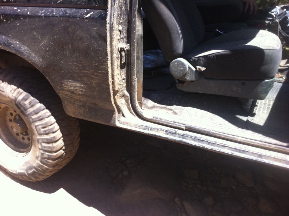 1990 Ford Bronco interior showing driver's seat and muddy door frame