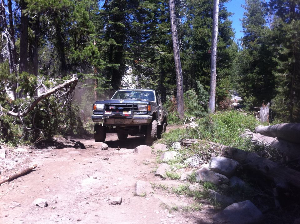 1990 Ford Bronco navigating a rocky, wooded trail