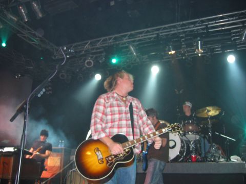 1989 Ford Bronco - A band plays live on stage under bright lights, with a guitarist in the foreground.