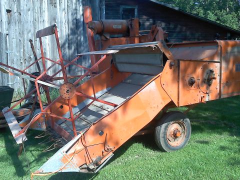 2000 Chevrolet Tahoe - An orange combine harvester sits idle on a grassy area, with a weathered wooden barn in the background.