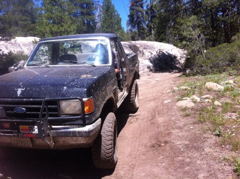 1990 Ford Bronco - This Ford truck is off-roading on a sunny day with a rocky landscape.