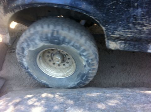 1990 Ford Bronco - Off-road tire and fender detail of a vehicle on sandy terrain.