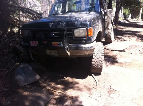 1990 Ford Bronco - 1990 Ford Bronco navigating a rocky trail in a wooded area.