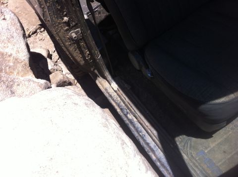 1990 Ford Bronco - Close-up of a vehicle's interior door and seat, showing signs of off-road use with mud and rocks visible.