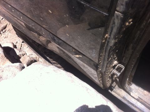 1990 Ford Bronco - The door and frame of a vehicle appear to be damaged, with debris around it.
