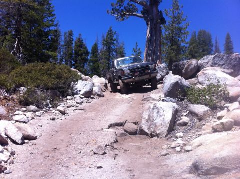 1990 Ford Bronco - A 1987 Ford Bronco navigates a challenging rocky terrain under a clear blue sky.