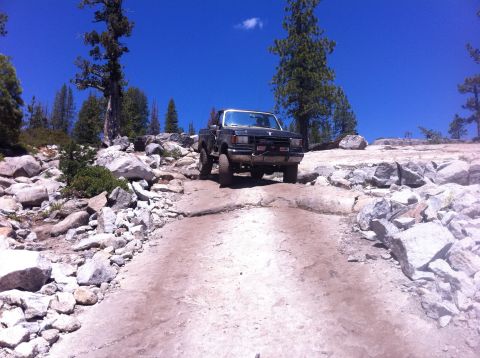 1990 Ford Bronco - This 1990 Ford Bronco navigates a challenging rocky terrain under a clear blue sky.