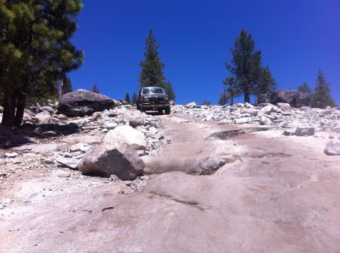 1990 Ford Bronco - 1990 Ford Bronco navigating a challenging rocky path in a mountainous, arid landscape.