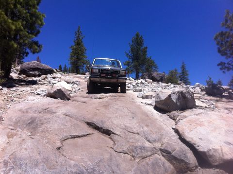 1990 Ford Bronco - This 1990 Ford Bronco navigates a challenging rocky trail under a clear blue sky.