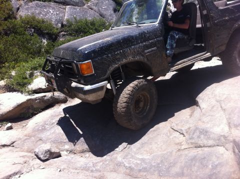 1990 Ford Bronco - Ford Bronco tackling a challenging off-road trail with large rocks.