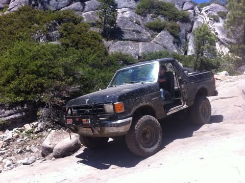 1990 Ford Bronco - 1990 Ford Bronco navigating a challenging rocky trail during an off-road excursion.