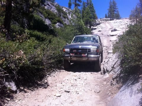 1990 Ford Bronco - 1990 Ford Bronco navigates a challenging rocky trail during an off-road excursion.