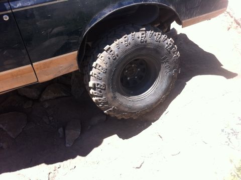 1990 Ford Bronco - Close-up of a 1990 Ford Bronco's front wheel and fender on rocky terrain.