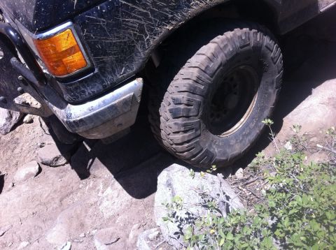 1990 Ford Bronco - Front wheel and fender of a 1990 Ford Bronco navigating rocky terrain.