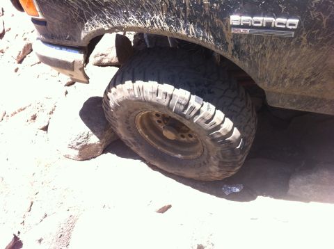 1990 Ford Bronco - A black Ford Bronco navigates a rocky trail, showing its off-road capabilities.