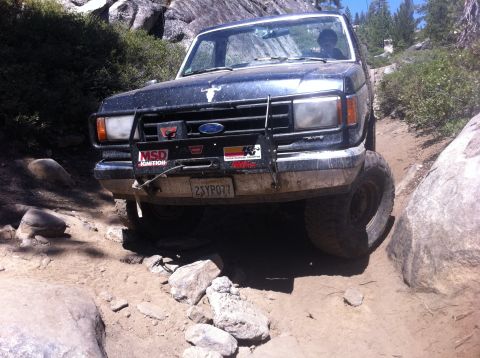 1990 Ford Bronco - This 1990 Ford Bronco navigates a challenging rocky trail, its front bull bar adorned with various stickers.