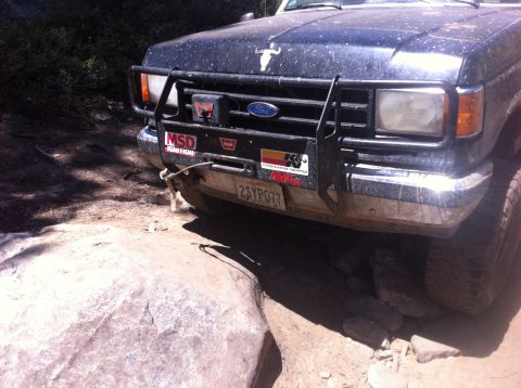1990 Ford Bronco - Ford Bronco navigating a rocky off-road trail, equipped with a brush guard and winch.