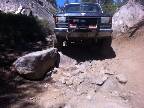 1990 Ford Bronco - This Ford truck is shown on a challenging, rocky off-road trail with large boulders.