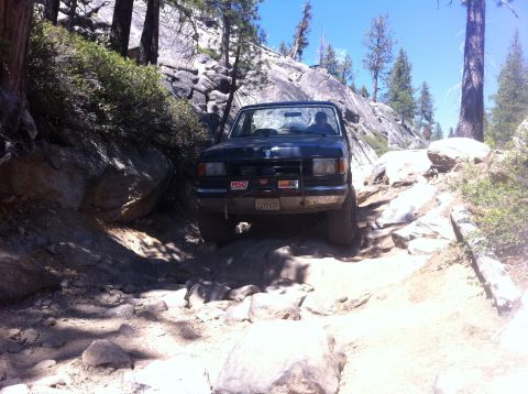 1990 Ford Bronco - A black 1990 Ford Bronco navigates a challenging rocky off-road path.