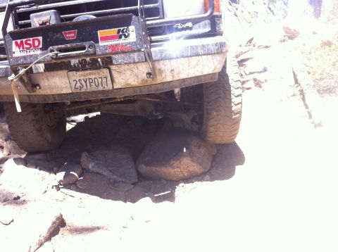1990 Ford Bronco - 1990 Ford Bronco navigating rocky terrain, front tire and bumper are on large rocks.