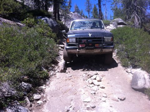 1990 Ford Bronco - A black Ford Bronco navigates a challenging rocky off-road path.