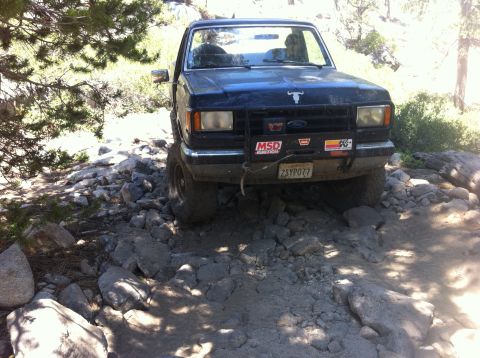 1990 Ford Bronco - 1990 Ford Bronco tackling a challenging rocky path during an off-road excursion.