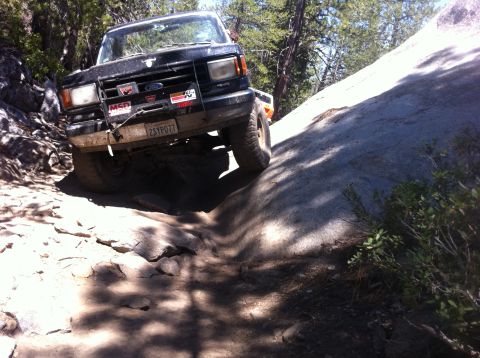 1990 Ford Bronco - This Ford Bronco is navigating a challenging rocky terrain on an off-road trail.