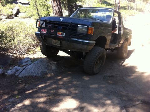 1990 Ford Bronco - This modified Ford Bronco navigates a rocky, off-road trail with its front tire lifted.