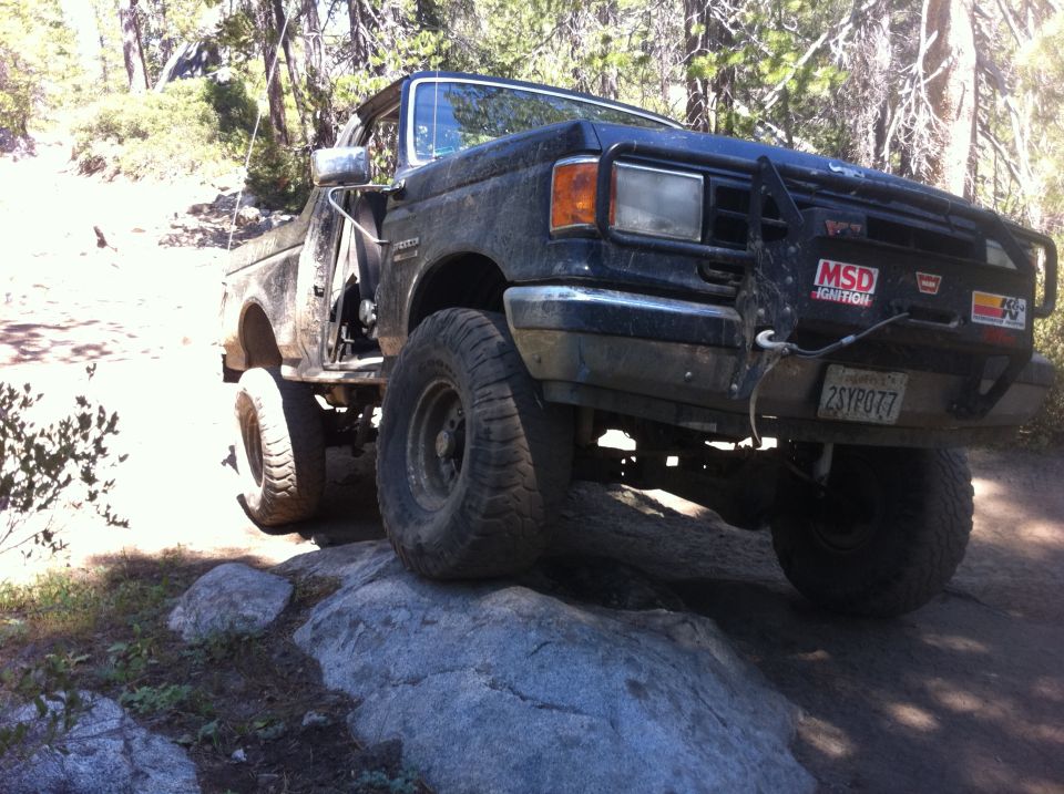 1990 Ford F-Series truck with aftermarket bumper and MSD Ignition sticker, driving on rocks