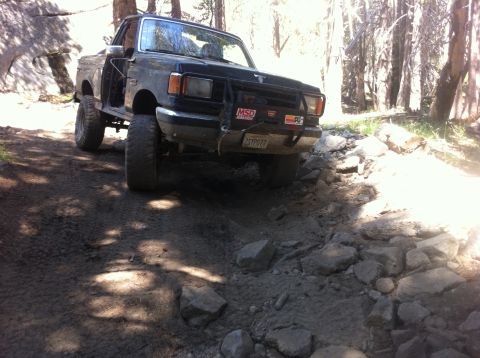1990 Ford Bronco - This 1990 Ford Bronco is shown tackling a challenging, rocky trail in a wooded area.