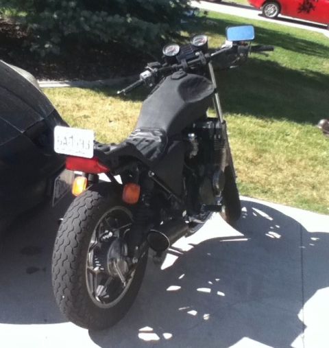 2002 Kawasaki Ninja - A motorcycle is parked on a driveway next to a black car. The motorcycle has a black seat and exhaust pipes.
