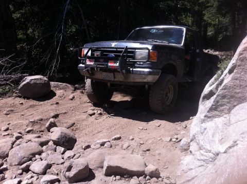1990 Ford Bronco - This black Ford F-Series truck navigates a challenging rocky path, suggesting it's built for off-road adventures.