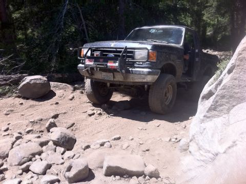 1990 Ford Bronco - This 1990 Ford Bronco is shown tackling a challenging, rocky trail in a wooded area.