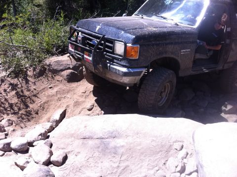 1990 Ford Bronco - This 1990 Ford Bronco is shown tackling a challenging off-road trail with large rocks and steep inclines.
