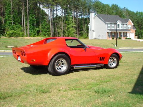 1976 Chevrolet Corvette - A red 1975 Chevrolet Corvette is parked on a grassy lawn in front of a house.