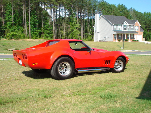 Red 1975 Chevrolet Corvette with side pipes parked on grass